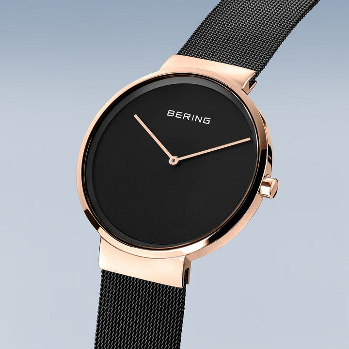 Berings 14539-166 horloge heeft een minimalistisch design met een cijferloze zwarte wijzerplaat, roségouden wijzers en roestvrijstalen kast geaccentueerd door een roségouden lunette. De zwarte mesh band verbetert de Quartz-uurwerk precisie en elegantie.
