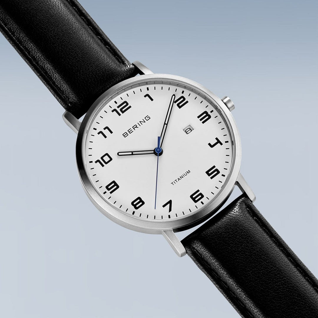 Het Bering herenhorloge 18640-404 heeft een titanium kast met een minimalistische witte wijzerplaat, zwarte Arabische cijfers, datumvenster op 3 uur, blauwe secondewijzer, Quartz-uurwerk, zwarte leren band en Bering op de zilveren kast.