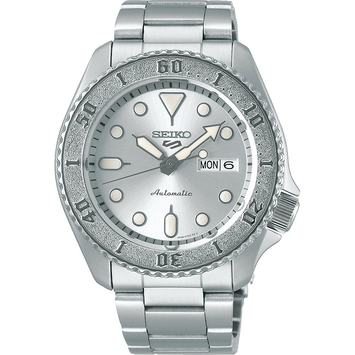 De Seiko 5 Sports heren horloge SRPE71K1 van Seiko heeft een zilverkleurige metalen band, een lunette met structuur en een ronde wijzerplaat met opvallende uurmarkeringen en wijzers. De dag en datum worden weergegeven op 3 uur.
