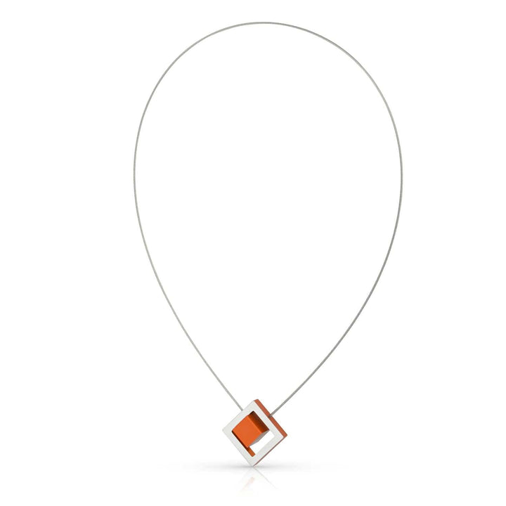De Collier Kubus in vierkant C25O oranje van CLIC Creations is een minimalistische, handgemaakte Nederlandse ketting met een dunne zilveren draad en een geometrische hanger met een oranje vierkant in een zilveren frame in het midden.