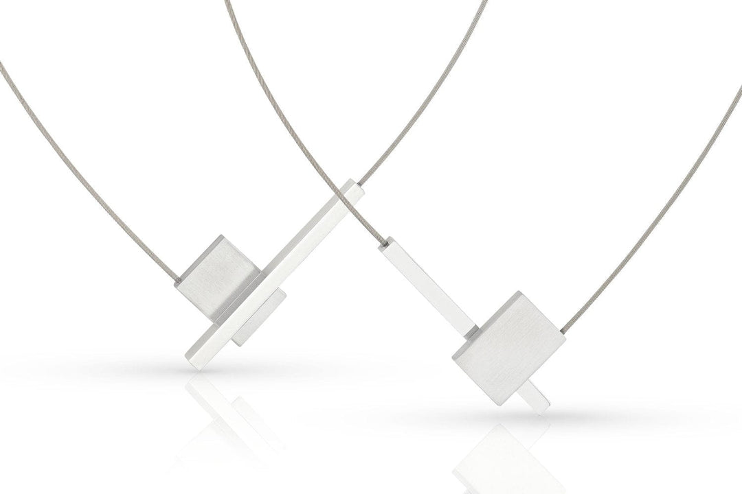 De Collier V-vorm met staafje C261 van CLIC Creations heeft een minimalistisch design met een geometrische rechthoekige hanger aan een dunne ketting en een makkelijke magnetische sluiting, afgebeeld op een witte achtergrond. Dit unieke stuk is handgemaakt in Nederland.