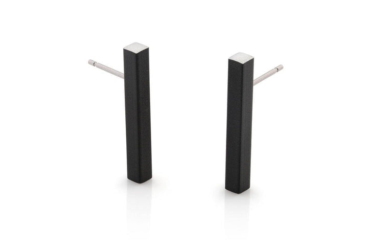 De Oorsteker Staafje Zwart O26Z van CLIC Creations is een paar minimalistische zwarte rechthoekige oorbellen met zilveren stekers, handgemaakt in Nederland. Ze hebben een strak design en matte afwerking, afgebeeld tegen een witte achtergrond voor een elegante touch.