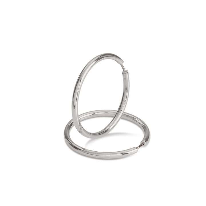 Een paar elegante Boccia Titanium Oorringen 05070-01 met een gladde, zilveren afwerking wordt getoond tegen een witte achtergrond – één rechtopstaand, één liggend. Deze tijdloze titanium oorbellen van Boccia vormen een perfecte aanvulling op elke sieradencollectie.